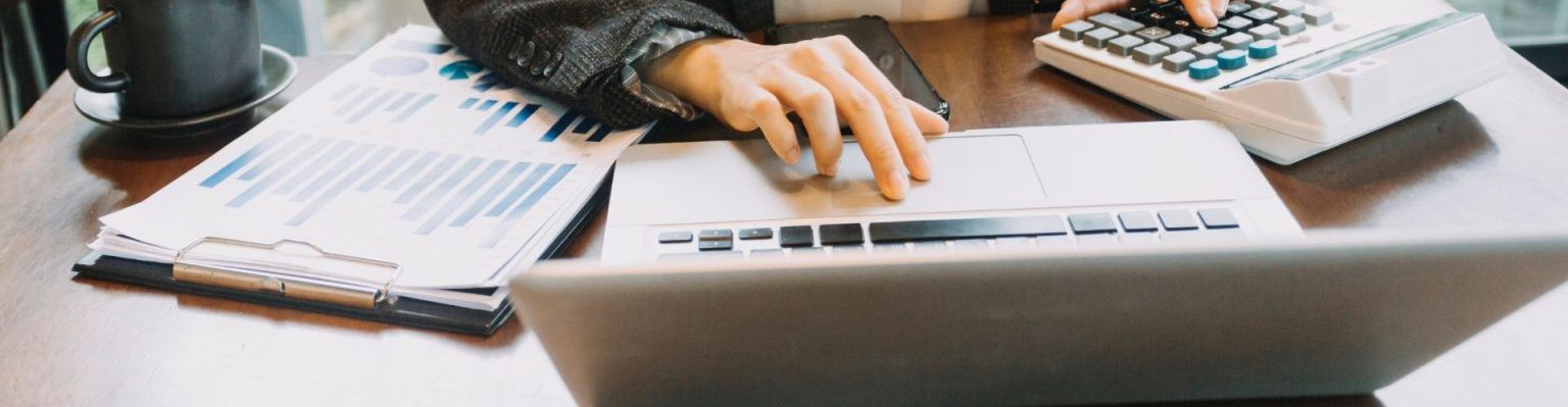 Financial services - Desk with calculator, laptop computer and reports.